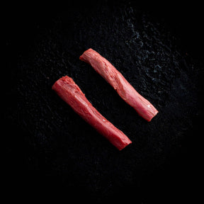 a couple of red hot dogs on a black surface 