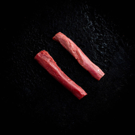 a couple of red hot dogs on a black surface 