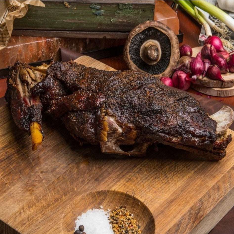 a plate of meat and vegetables on a wooden table 