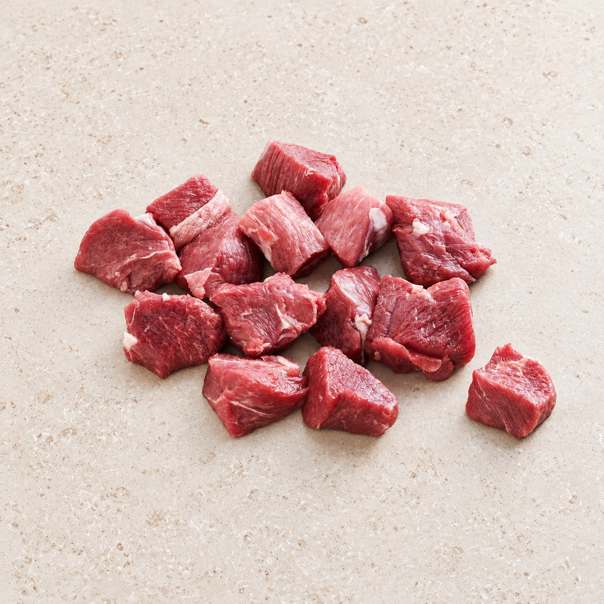 Raw beef chuck cubes on a light limestone surface.
