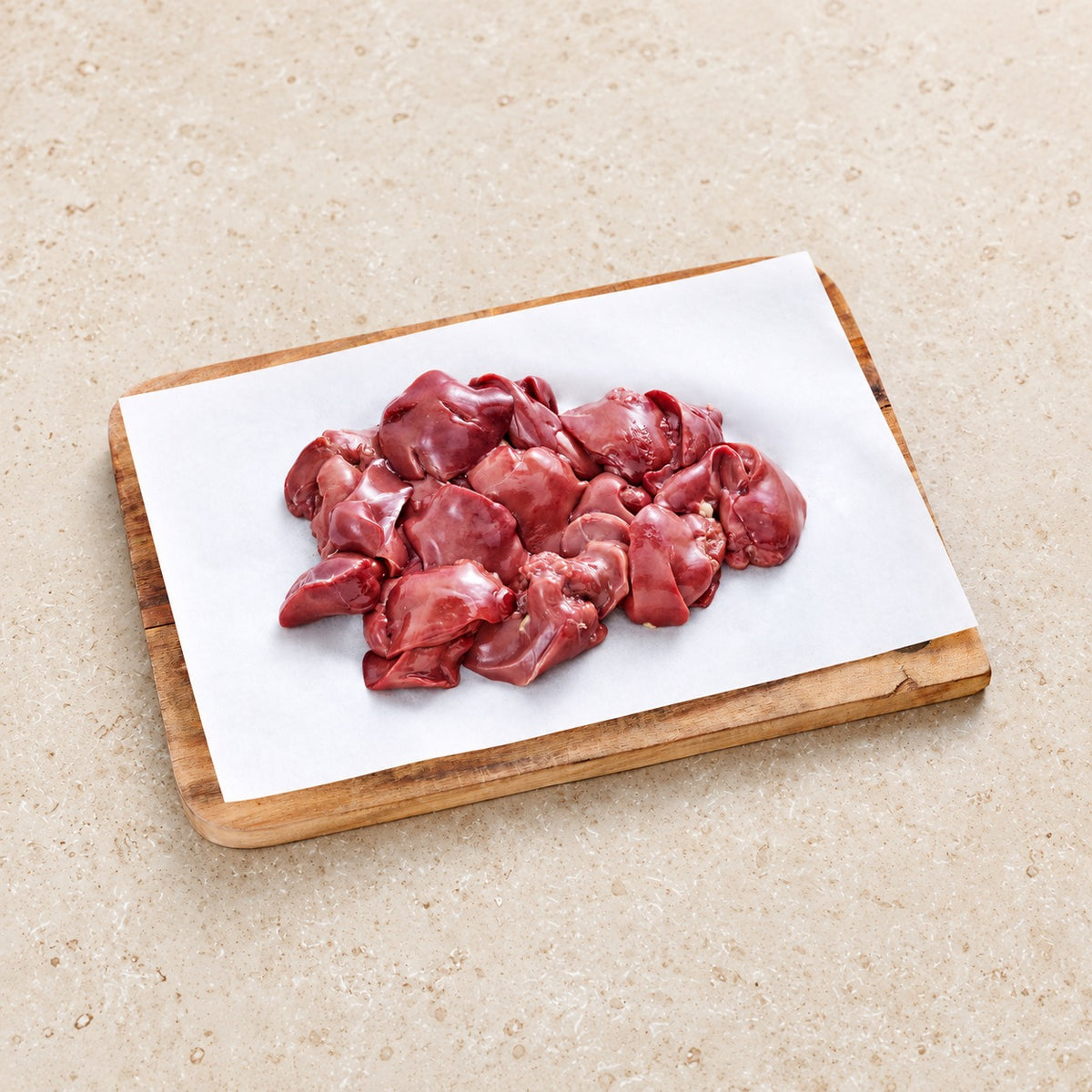 Raw chicken liver on butcher paper and a wooden board.