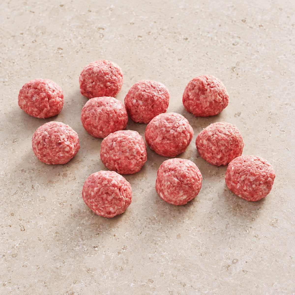 Twelve raw Wagyu slider smash burger portions on limestone.