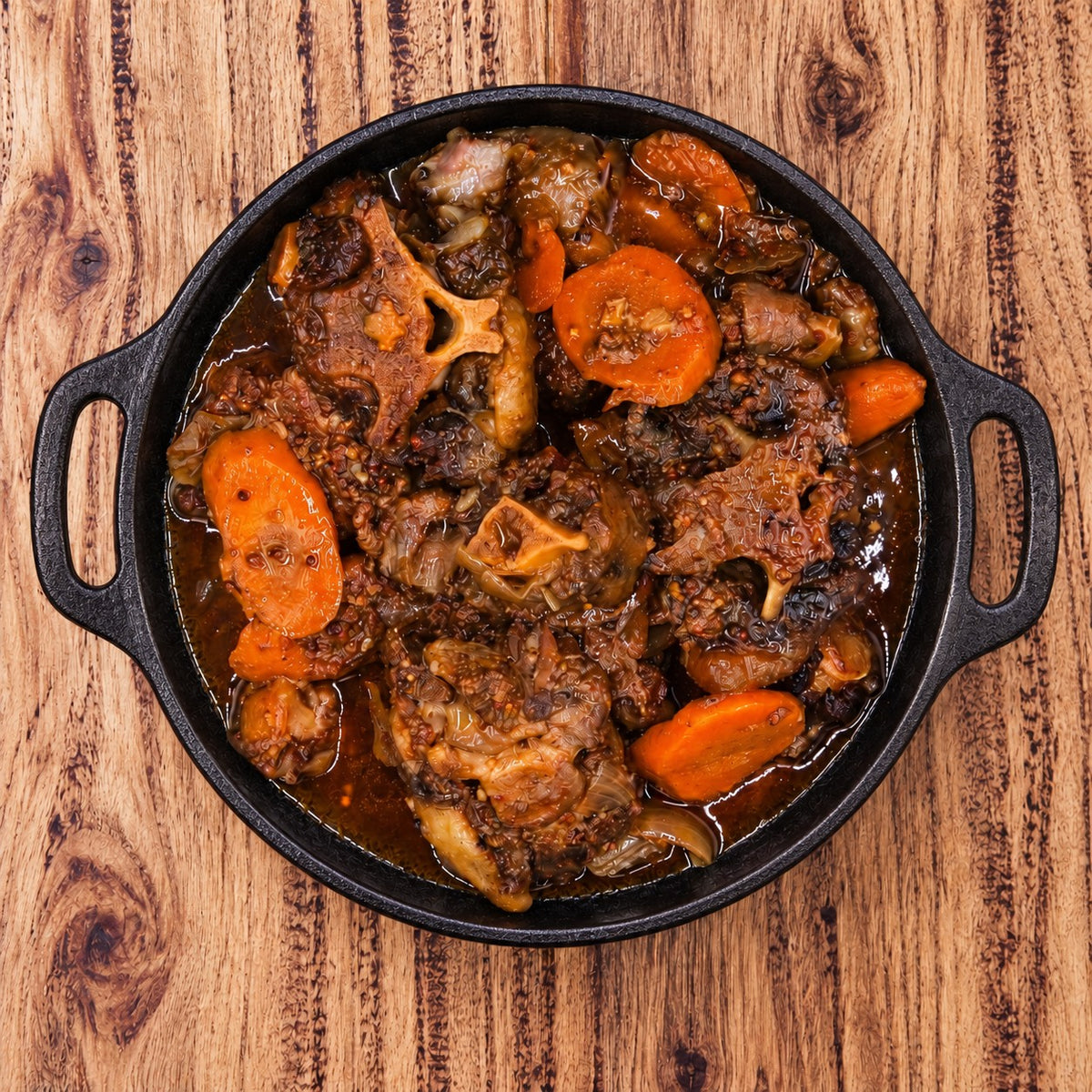 CarniStore smoked oxtail stew with carrots and onions in rich broth, served in a black cast-iron dish.